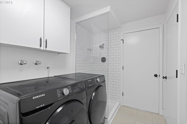 clothes washing area with light tile patterned floors, washing machine and dryer, and cabinets