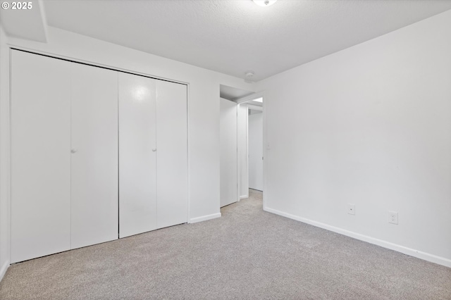 unfurnished bedroom with light colored carpet and a closet