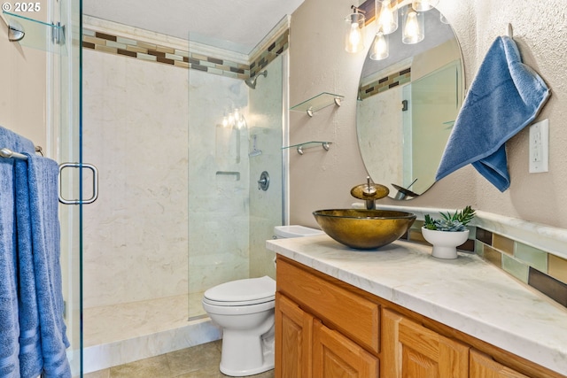 3473 Parker Ln, Springfield, OR 97477 - full bathroom with a stall shower, vanity, a textured wall, toilet, and tile patterned flooring
