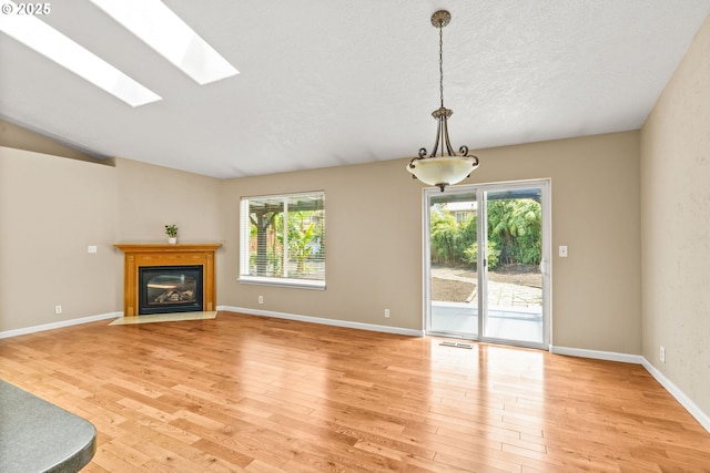 3473 Parker Ln, Springfield, OR 97477 - unfurnished living room featuring light wood-style floors, healthy amount of natural light, a fireplace with flush hearth, and a textured ceiling