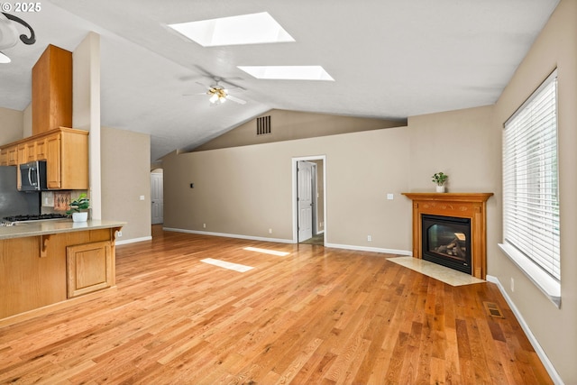 3473 Parker Ln, Springfield, OR 97477 - unfurnished living room featuring a skylight, lofted ceiling, light wood-style flooring, a fireplace with flush hearth, and plenty of natural light