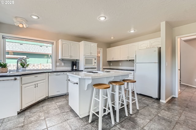 22160 NE Lachenview Ln, Fairview, OR 97024 - kitchen with white appliances, a sink, a center island, white cabinets, and a kitchen breakfast bar