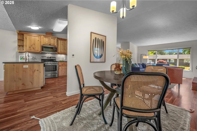 1629 NW Orchard Ave, Gresham, OR 97030 - dining space featuring wood finished floors, a textured ceiling, a chandelier, and baseboards