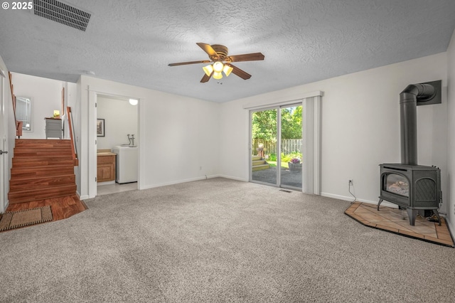 1629 NW Orchard Ave, Gresham, OR 97030 - unfurnished living room featuring carpet, ceiling fan, a wood stove, stairs, and a textured ceiling