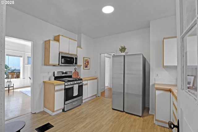 26 NW 22nd Pl, Portland, OR 97210 - kitchen featuring stainless steel appliances, light wood finished floors, white cabinets, and wooden counters