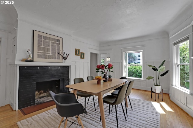 26 NW 22nd Pl, Portland, OR 97210 - dining area featuring a decorative wall, a fireplace, light wood-style floors, and a wainscoted wall