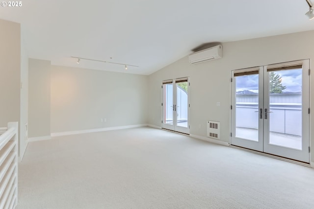 325 NE Graham St Unit 10, Portland, OR 97212 - empty room featuring french doors, rail lighting, a wall mounted air conditioner, light colored carpet, and vaulted ceiling