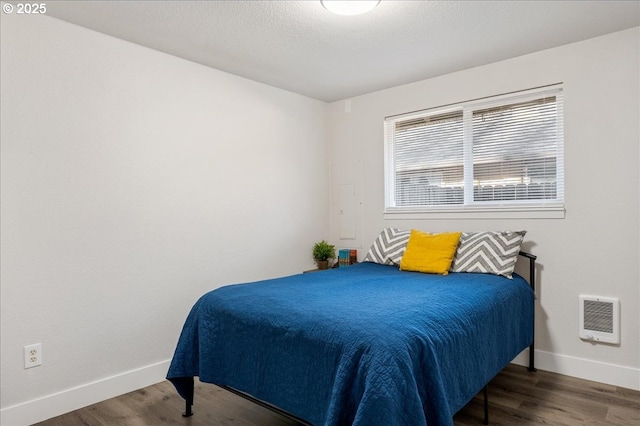 bedroom with dark wood-type flooring and heating unit