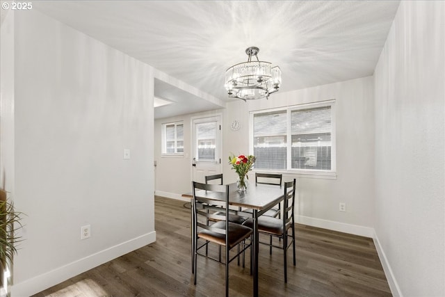 dining space with dark wood-type flooring and a notable chandelier