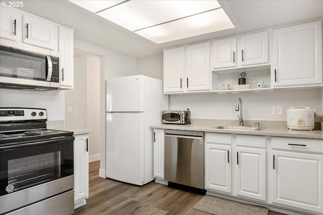 kitchen with light stone countertops, dark hardwood / wood-style flooring, stainless steel appliances, sink, and white cabinets