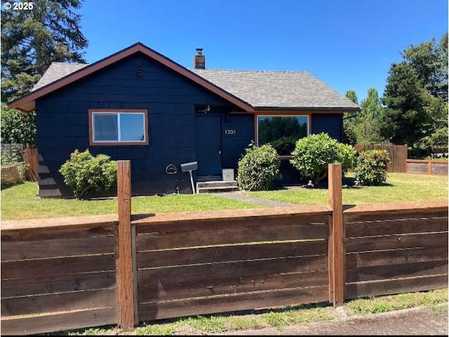 exterior space featuring a yard, roof with shingles, a chimney, and fence