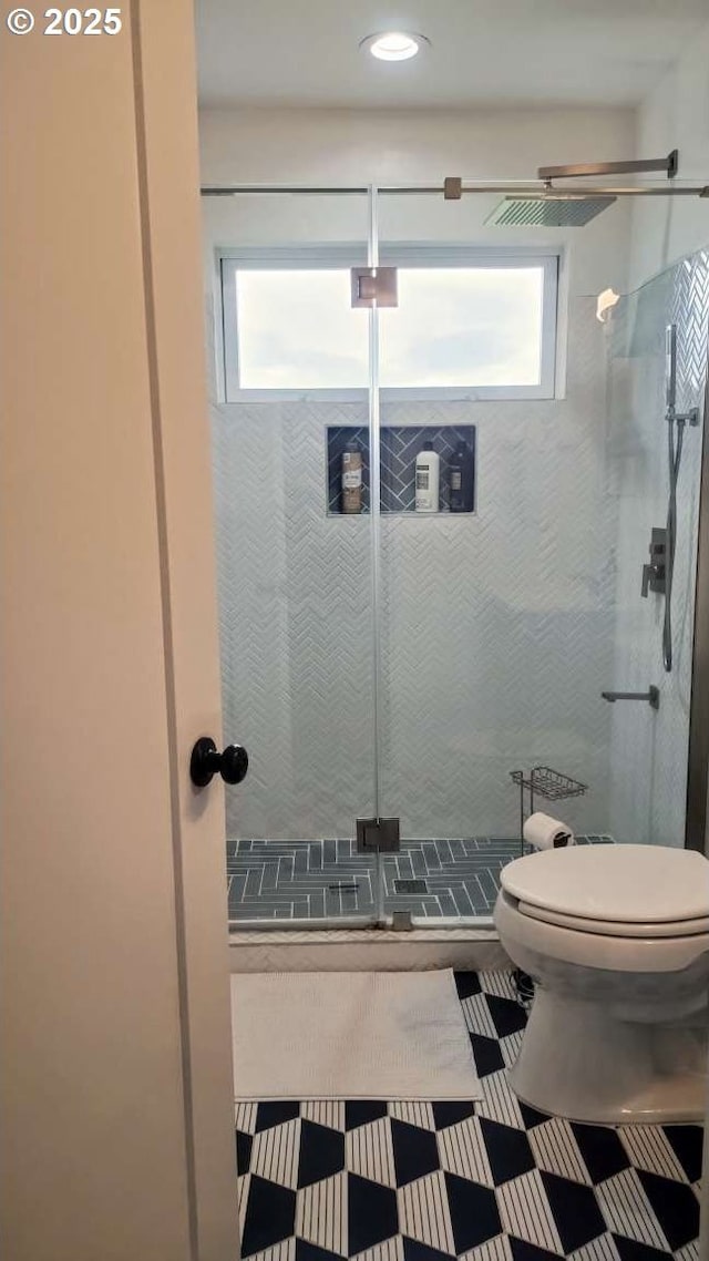 bathroom featuring toilet, a stall shower, and tile patterned flooring