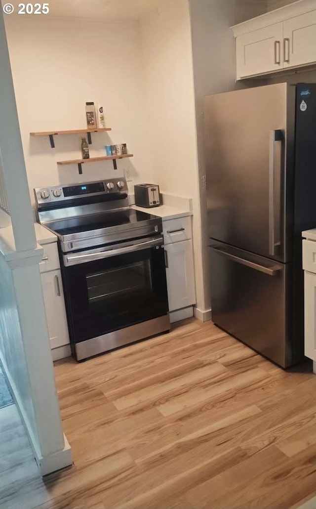 kitchen with stainless steel appliances, light wood-style floors, light countertops, and white cabinetry