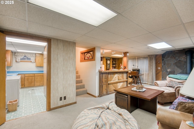living area with a drop ceiling, washer / dryer, light carpet, bar area, and baseboards