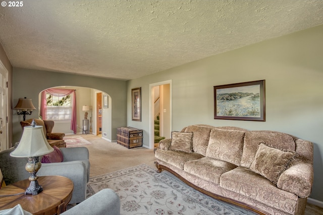 living area featuring arched walkways, a textured ceiling, carpet flooring, and baseboards