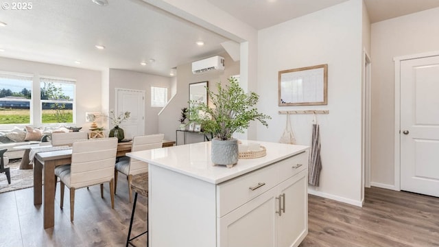 3447 SW Thomas Ave, Gresham, OR 97080 - kitchen with light wood-type flooring, a wall unit AC, a center island, white cabinets, and light countertops