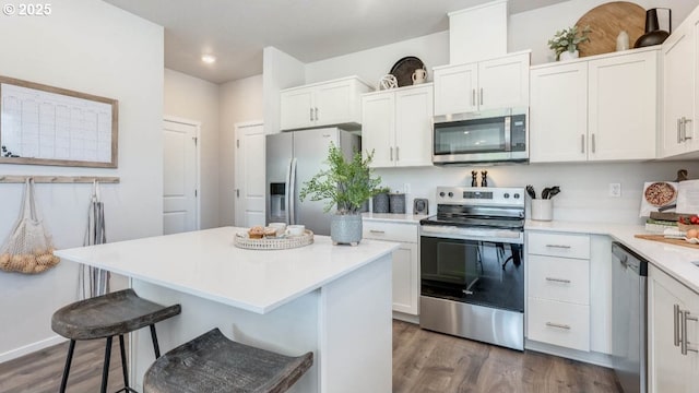 3447 SW Thomas Ave, Gresham, OR 97080 - kitchen with appliances with stainless steel finishes, a kitchen breakfast bar, dark wood-style flooring, white cabinetry, and recessed lighting