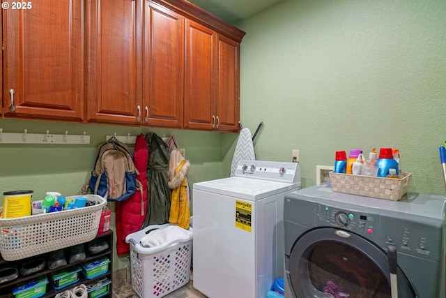 laundry room with cabinet space, a textured wall, and washing machine and clothes dryer