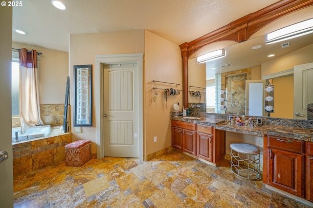 bathroom featuring a garden tub, stone finish flooring, visible vents, and vanity