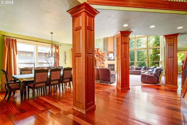 dining room featuring a healthy amount of sunlight, ornate columns, a wall of windows, and wood finished floors