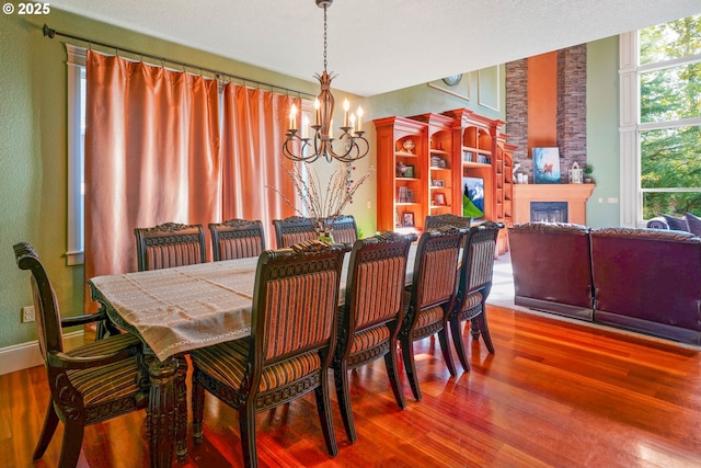 dining space with a fireplace, wood finished floors, and an inviting chandelier