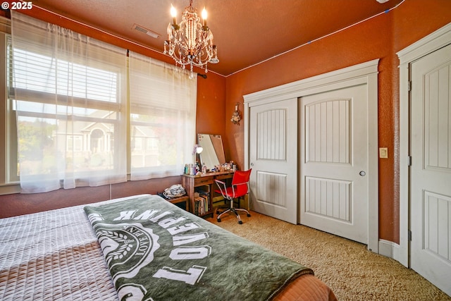 bedroom featuring a closet, carpet flooring, visible vents, and an inviting chandelier