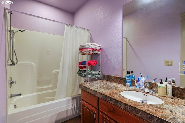 bathroom featuring a textured wall, shower / tub combo with curtain, and vanity