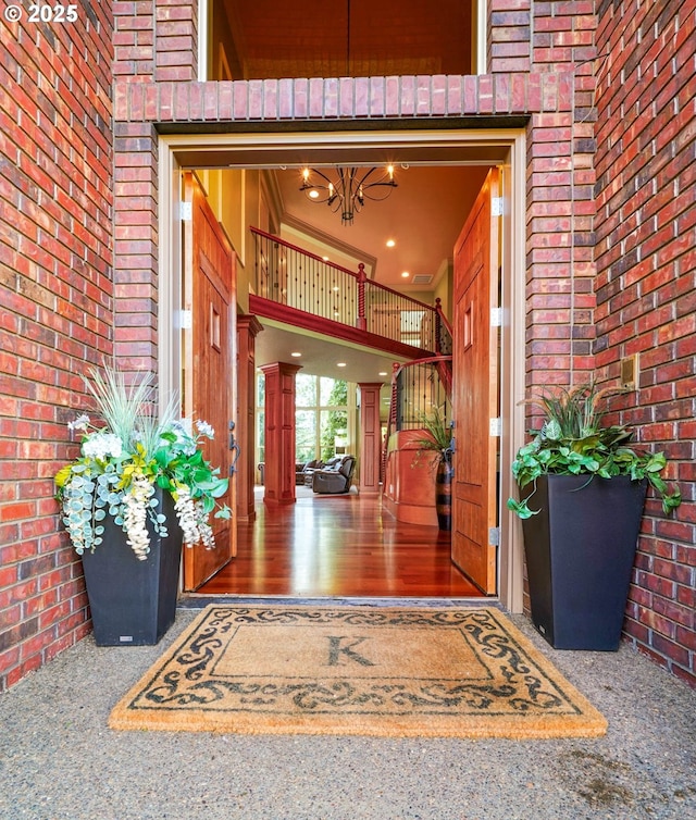 view of exterior entry with a balcony and brick siding