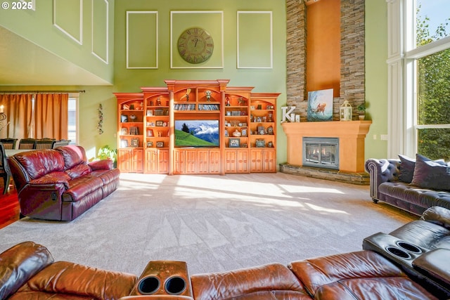 carpeted living room featuring a large fireplace and a high ceiling