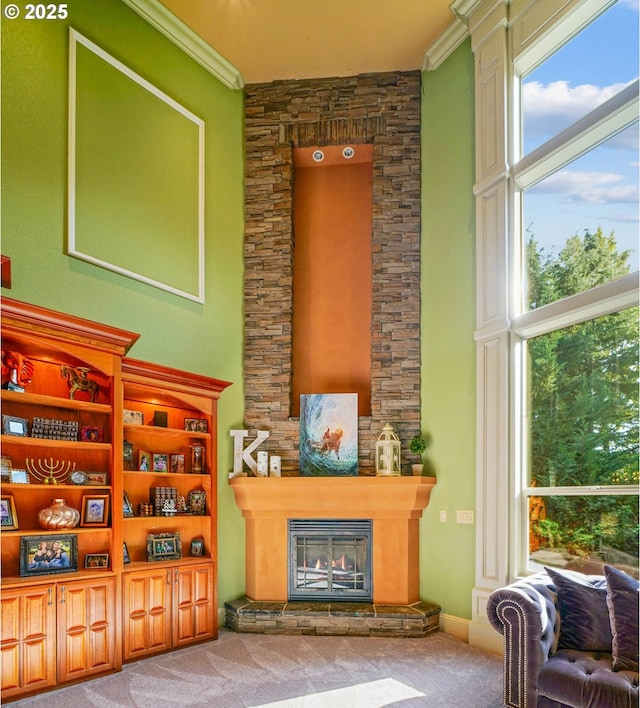 interior space featuring a glass covered fireplace, carpet flooring, crown molding, and a towering ceiling