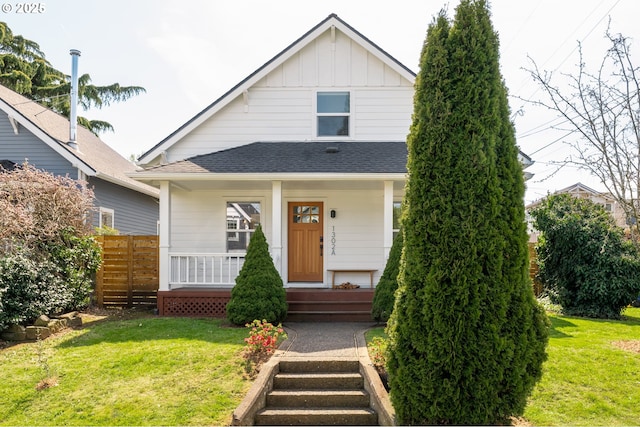 bungalow featuring a front lawn, board and batten siding, fence, and covered porch
