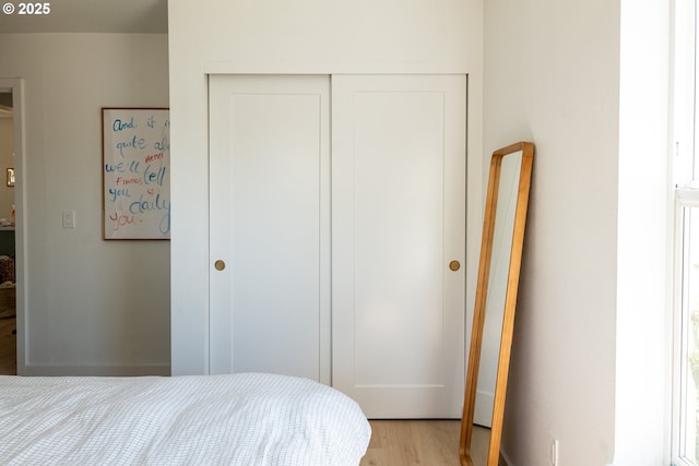 bedroom with light wood finished floors and a closet