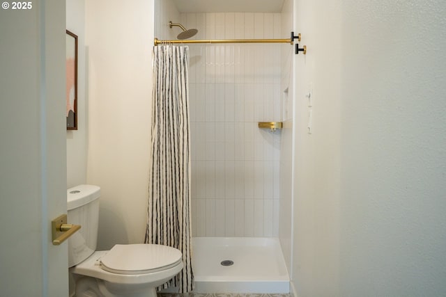 bathroom with a shower stall and toilet