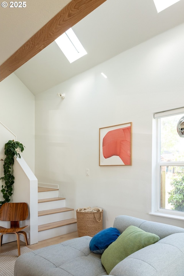 living room featuring a skylight, wood finished floors, high vaulted ceiling, beamed ceiling, and stairs