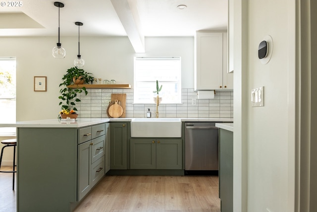 kitchen featuring stainless steel dishwasher, light countertops, backsplash, and light wood-type flooring