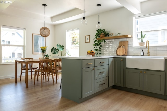 kitchen with light countertops, a sink, light wood-style flooring, and tasteful backsplash