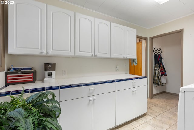 12791 Sutherland Rd, Swisshome, OR 97480 - kitchen with white cabinets, light tile patterned floors, washer / clothes dryer, and baseboards