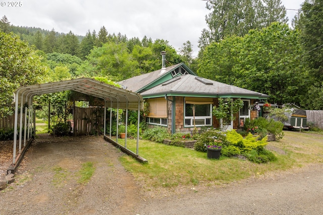 12791 Sutherland Rd, Swisshome, OR 97480 - view of front of home with dirt driveway, a detached carport, and a wooded view