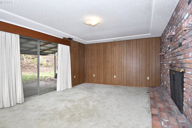 unfurnished living room featuring carpet flooring, a textured ceiling, wooden walls, and a fireplace