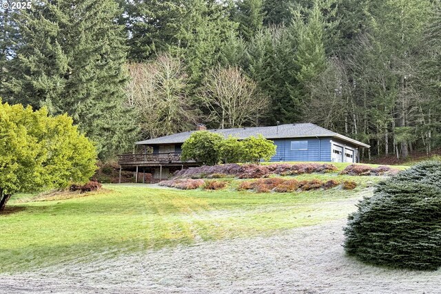 view of front of house with a view of trees, a garage, a chimney, and a front lawn