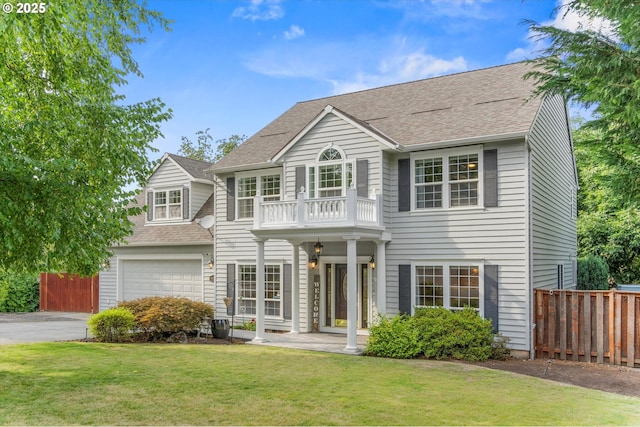 view of front of property featuring a balcony, a garage, and a front yard