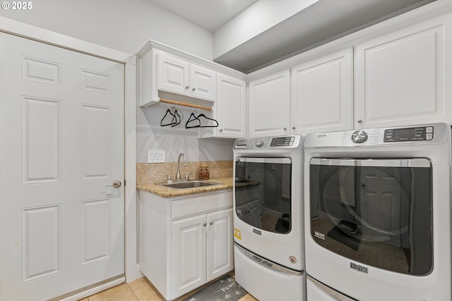 clothes washing area with sink, light tile patterned floors, cabinets, and washing machine and clothes dryer