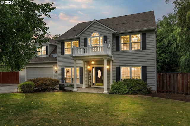 colonial house featuring a yard, a garage, and a balcony