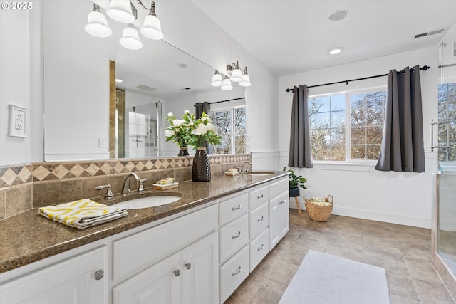 bathroom featuring tasteful backsplash, vanity, and a shower with door