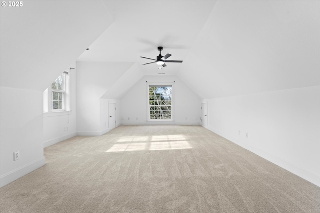 additional living space with lofted ceiling, ceiling fan, light colored carpet, and a healthy amount of sunlight