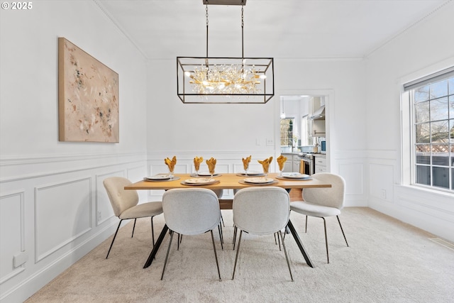 dining room featuring crown molding, plenty of natural light, a chandelier, and light carpet