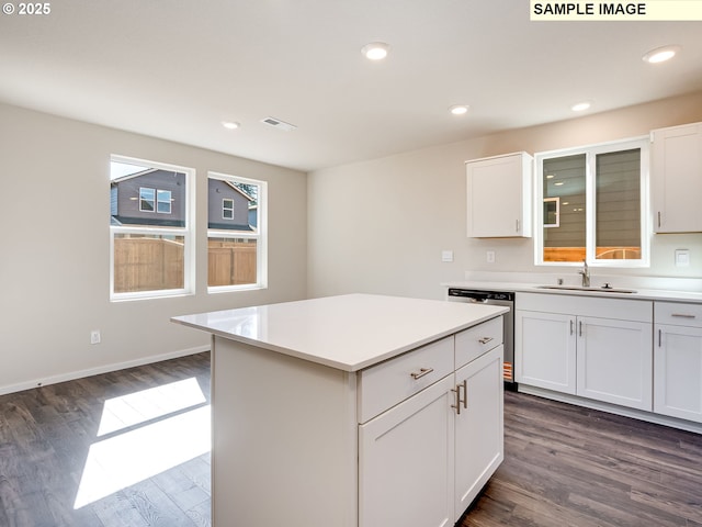 kitchen featuring a sink, dishwasher, dark wood finished floors, light countertops, and white cabinets