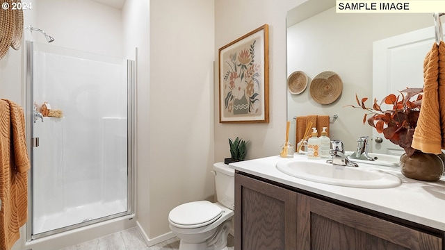 bathroom featuring vanity, toilet, and a shower with shower door