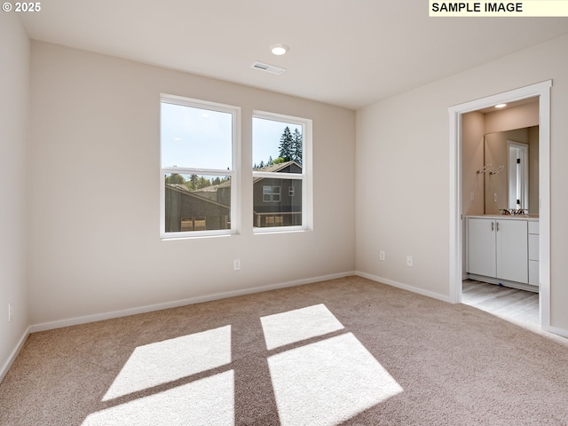 unfurnished bedroom featuring carpet floors, baseboards, recessed lighting, and ensuite bath