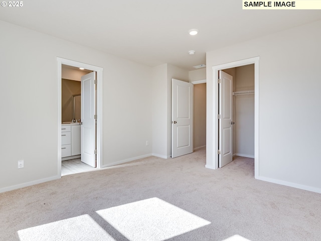 unfurnished bedroom with light colored carpet, baseboards, recessed lighting, a walk in closet, and ensuite bathroom